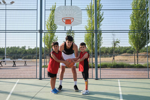 istock Three brothers looking at camera with a basketball, one has a leg prosthesis. 1332107972