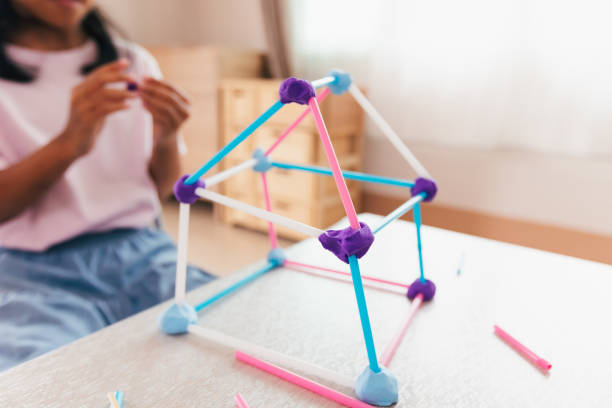 menina asiática bonita brincando e criando com playdough e canudos. criança concentrada com playdough construindo um modelo de molécula. - skill child mathematics physics - fotografias e filmes do acervo