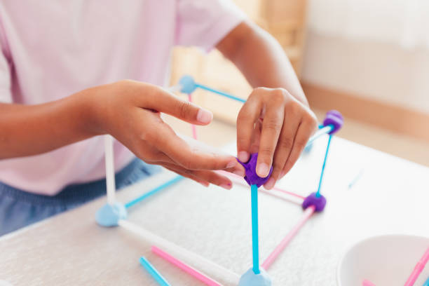 menina asiática bonita brincando e criando com playdough e canudos. criança concentrada com playdough construindo um modelo de molécula. - skill child mathematics physics - fotografias e filmes do acervo