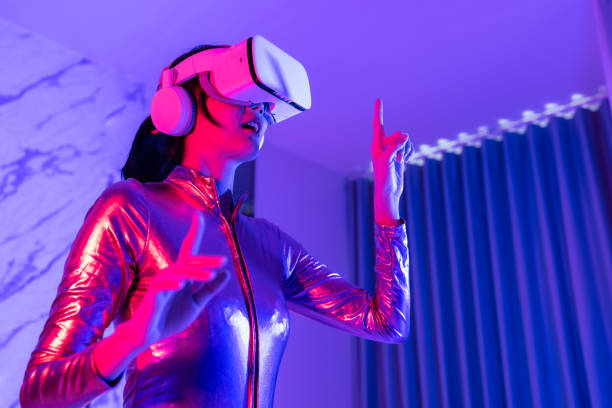 istock Young asian woman is using virtual reality headset. Neon light studio portrait. Concept of virtual reality, simulation, gaming and future technology.Asian woman play game in bedroom. 1332108301