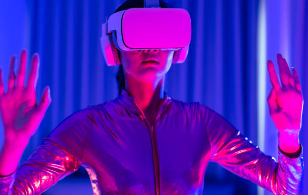 istock Young asian woman is using virtual reality headset. Neon light studio portrait. Concept of virtual reality, simulation, gaming and future technology.Asian woman play game in bedroom. 1332108396