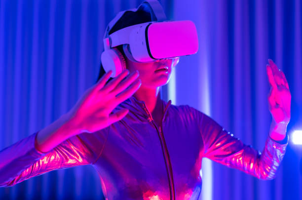 istock Young asian woman is using virtual reality headset. Neon light studio portrait. Concept of virtual reality, simulation, gaming and future technology.Asian woman play game in bedroom. 1332108521