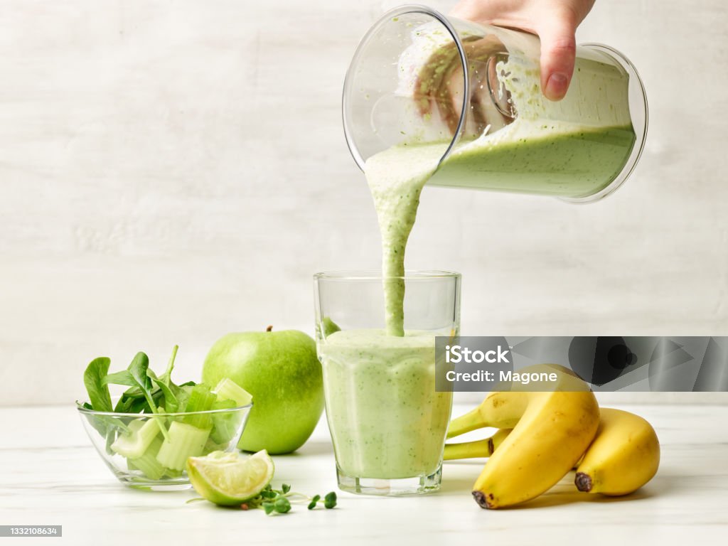 process of making healthy breakfast milkshake fresh green smoothie pouring into glass ready for healthy breakfast Smoothie Stock Photo