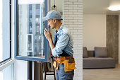 istock Construction Worker Installing New Windows In House 1332109922