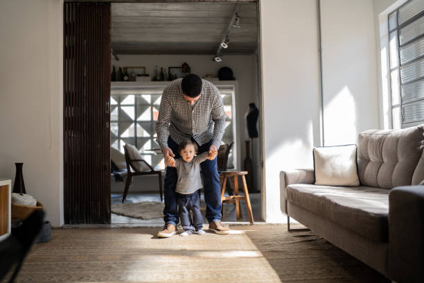 istock Father helping son with special needs taking his firt steps at home 1332111575