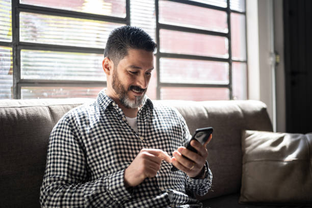 istock Mature man using smartphone on the couch at home 1332111587