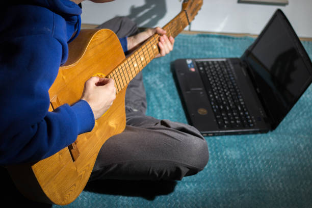 istock The guy is learning to play the guitar over the internet Online study 1332111974