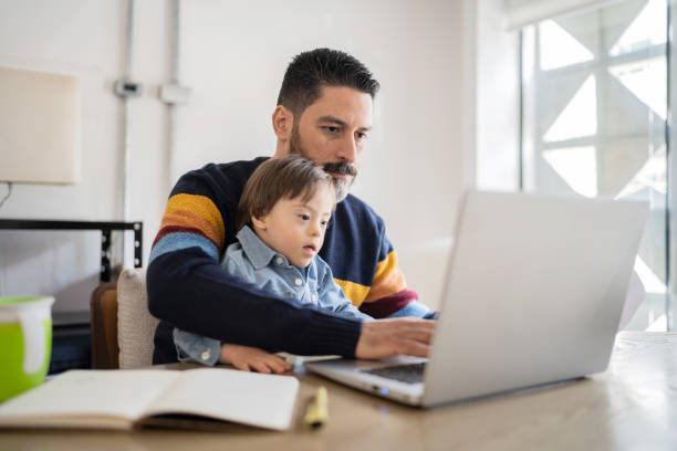 istock Mature man working at home with baby son - boy with special needs 1332112112