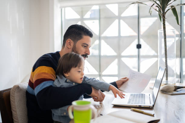 istock Mature man working at home with baby son - boy with special needs 1332112209