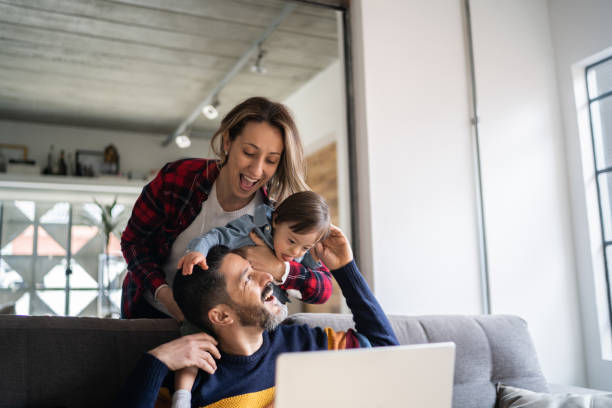 istock Man using laptop and being embraced by wife and special needs son at home 1332112218