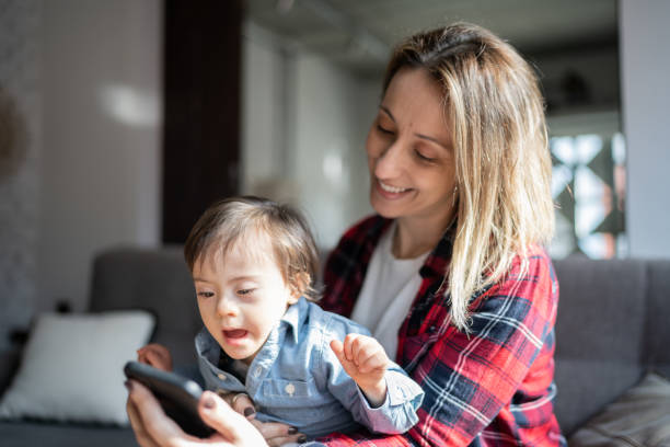 istock Mother and boy with special needs using mobile phone at home 1332112343