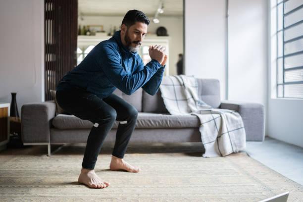 uomo maturo accovacciato a casa - crouching foto e immagini stock