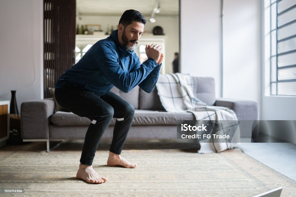 Mature man squatting at home Exercising Stock Photo