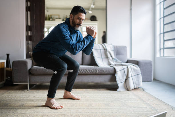 Mature man squatting at home Mature man squatting at home bodyweight training stock pictures, royalty-free photos & images