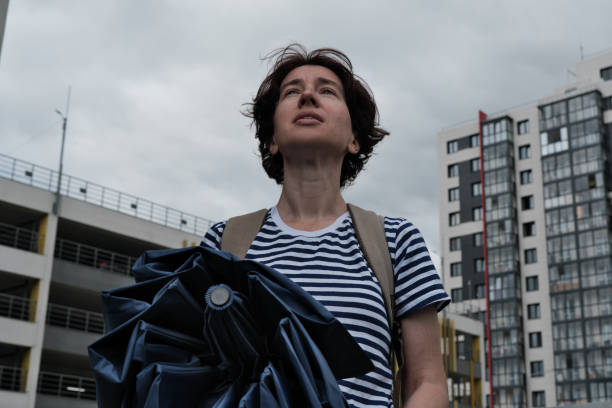 istock Woman is looking at the cloudy sky and using umbrella 1332113239