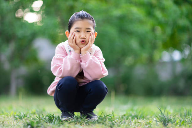 istock Cute Girl Squatting on the Grass 1332118647