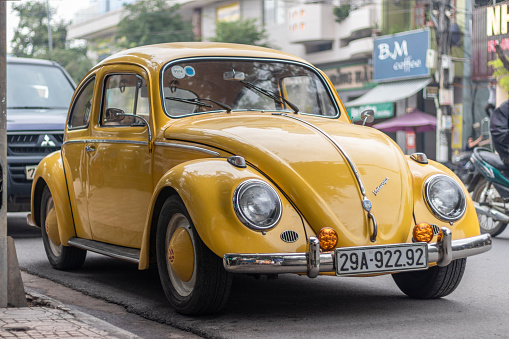 Nha Trang, Khanh Hoa Province, Vietnam - January 9, 2019: An old yellow Volkswagen beetle stands in a parking space near the sidewalk. Excellent condition