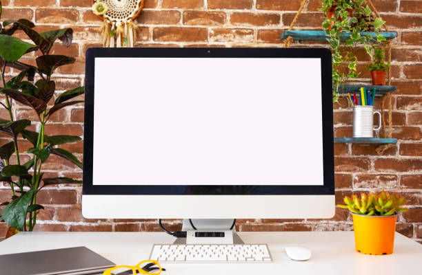 istock Blank screen computer in office room with accessories and copy space. Brick wall in background 1332119180