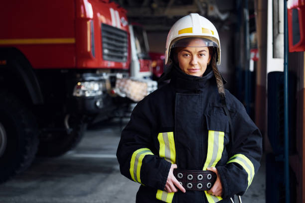 istock Female firefighter in protective uniform standing near truck 1332124263