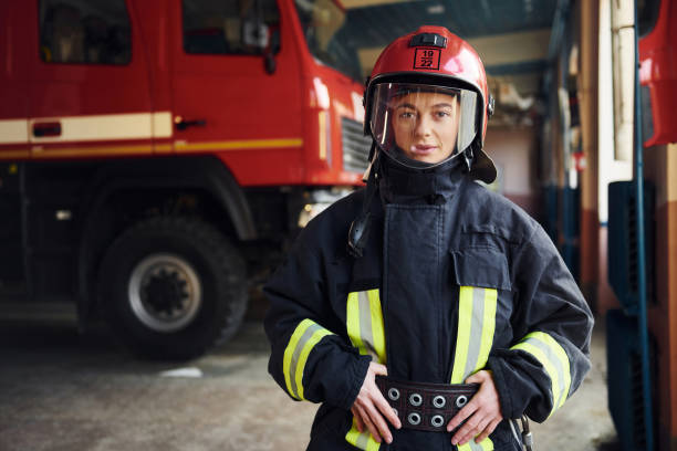 istock Female firefighter in protective uniform standing near truck 1332124357