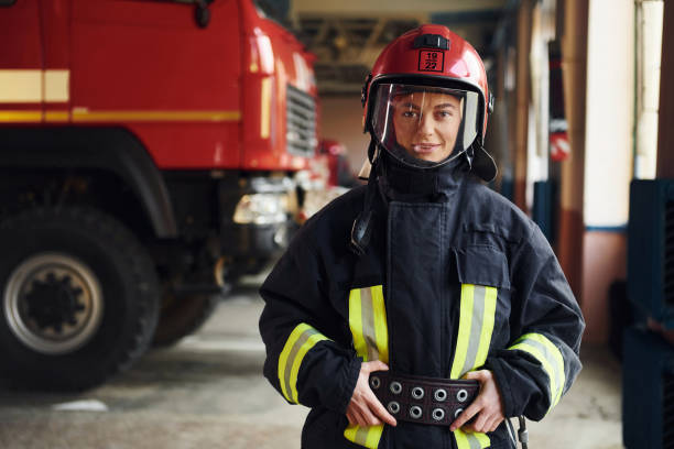istock Female firefighter in protective uniform standing near truck 1332124454