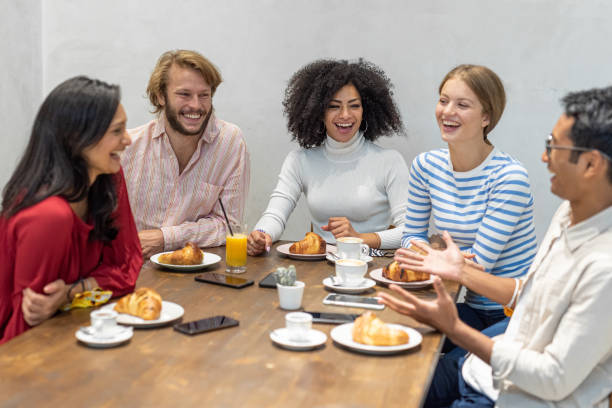 grupo de jovens millennials tomando café da manhã, trabalho em equipe em um momento de pausa, croissants e bolos, café e cappuccino na mesa de um bar - coffee couple italy drinking - fotografias e filmes do acervo