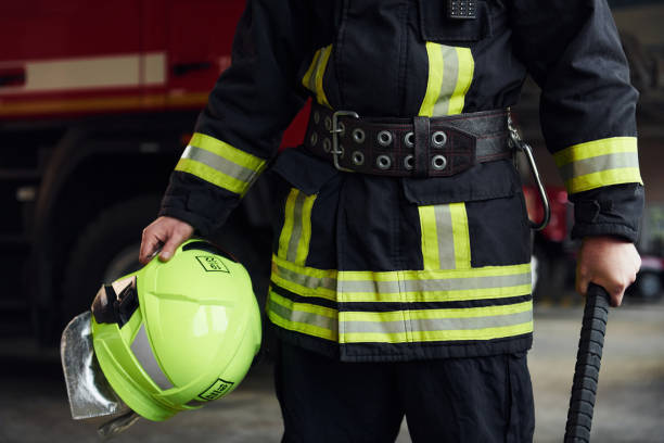 istock Male firefighter in protective uniform standing near truck 1332124704