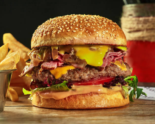 istock Hamburger with beef patty, ham, cheese, caramelized onion, greens and tomatoes 1332126162