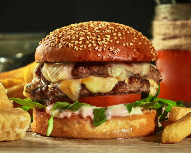 istock Burger with two patties, cheese, tomatoes and greens in sesame bun 1332126186