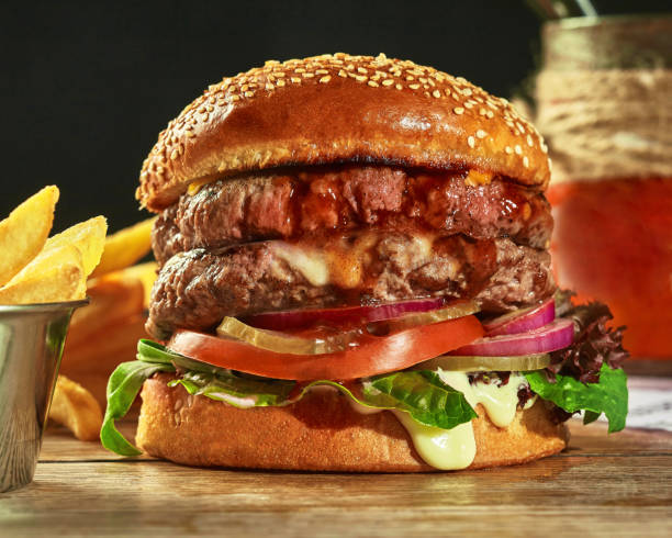 istock Double hamburger with two patties, pickles, tomatoes, onion, greens 1332126191