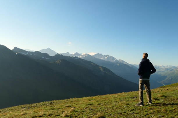 istock A hiker from the back, facing green mountains. 1332127177