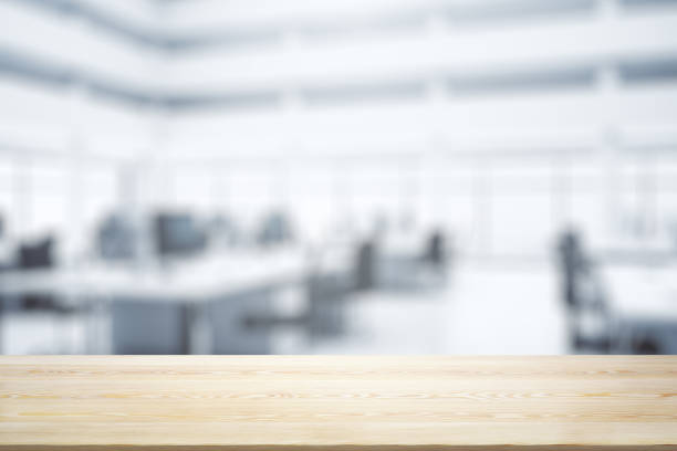 istock Blank wooden tabletop with bright furnished office on background, mockup 1332128182