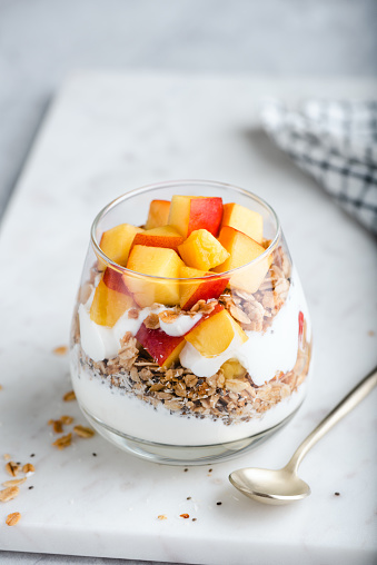 Yogurt granola parfait with peach in a glass. Healthy dessert food low in calories