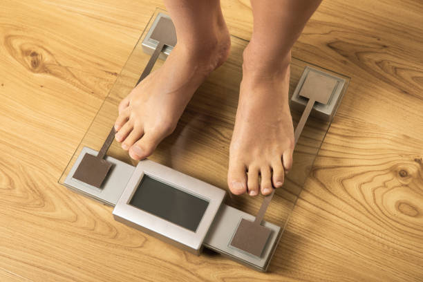 istock Female feet on the modern digital weighing scale 1332130533