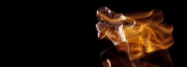 istock Flyer with young man, American football player training isolated on dark studio background with mixed neon light. Concept of sport, competition and beauty 1332130673