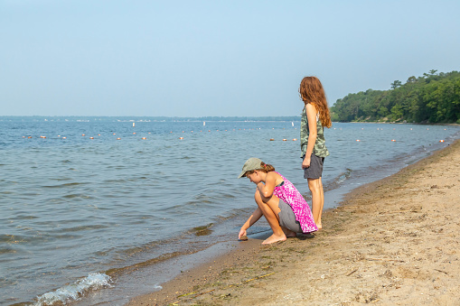 Two young girls (sisters) on the lakeshore of Lake Bemidji in Minnesota, USA.