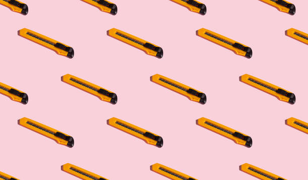 istock Stationery knives on a pink background, pattern, hard shadows. Construction tools, repairs. Background for the design. 1332131037