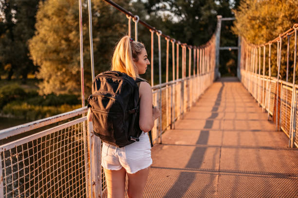 istock Female hiker walking over old bridge in nature 1332132103