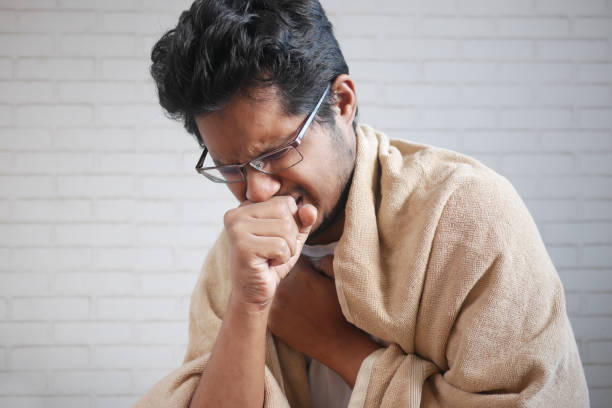 istock Mature man in blanket coughing while sited on bed 1332133639