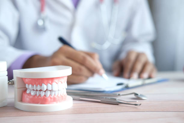 istock doctor hand writing prescription with plastic dental teeth model on table 1332133705