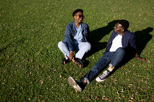 High angle view of a young happy African American couple having fun together in nature, sitting on the grass and enjoying themselves
