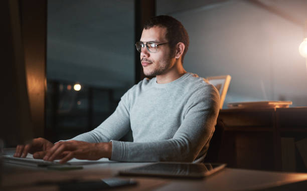 istock Shot of a young man using his computer at night at the office 1332137812
