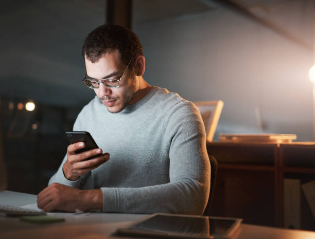 istock Shot of a young man using his cellphone while sitting at a desk at work 1332138736