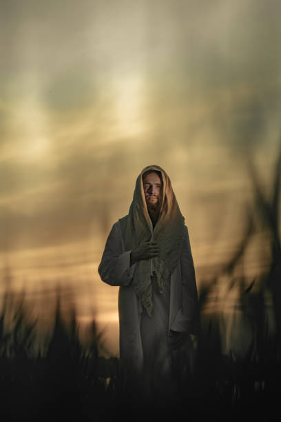 istock Jesus Christ walks in meadow in white robe at sunset. 1332138869