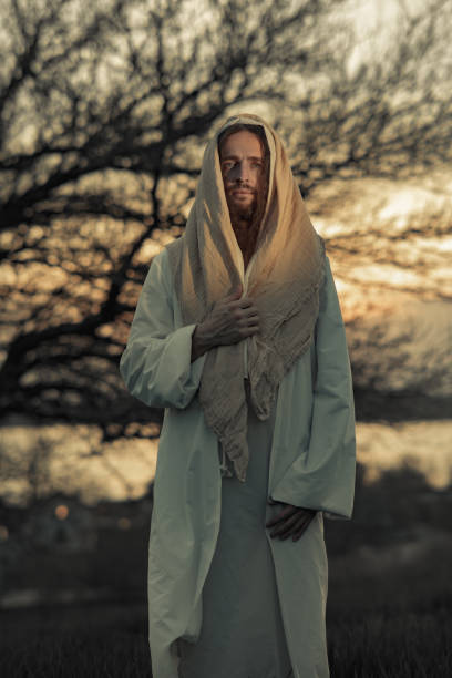 istock Jesus Christ walks in meadow in white robe at sunset. 1332138886