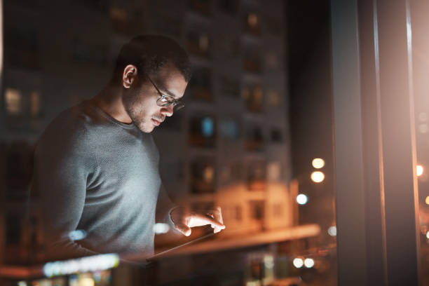 istock Shot of a young man using a digital tablet reflected in an office window 1332139214