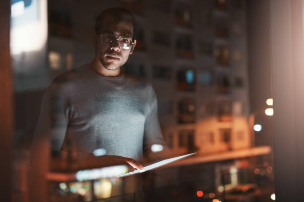 istock Shot of a young man using a digital tablet reflected in an office window 1332139247