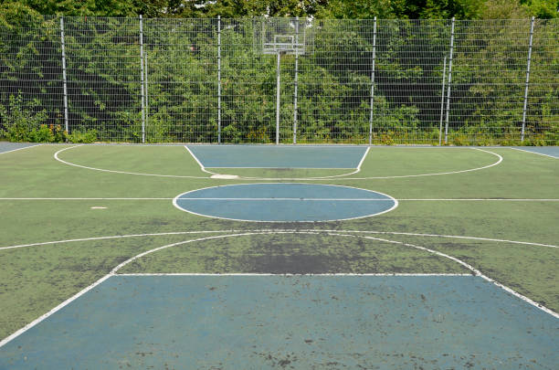 multifunctional outdoor playground for ball games at school. green artificial turf from a plastic carpet with lines. basketball hoops and soccer goals. around the grabbing high net and guardrails patio de recreo al aire libre multifuncional para juegos de pelota en la escuela. césped artificial verde de una alfombra de plástico con líneas. aros de baloncesto y goles de fútbol. alrededor de la red alta que agarra y de los barandillas