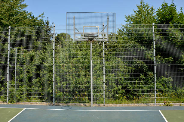 multifunctional outdoor playground for ball games at school. green artificial turf from a plastic carpet with lines. basketball hoops and soccer goals. around the grabbing high net and guardrails patio de recreo al aire libre multifuncional para juegos de pelota en la escuela. césped artificial verde de una alfombra de plástico con líneas. aros de baloncesto y goles de fútbol. alrededor de la red alta que agarra y de los barandillas