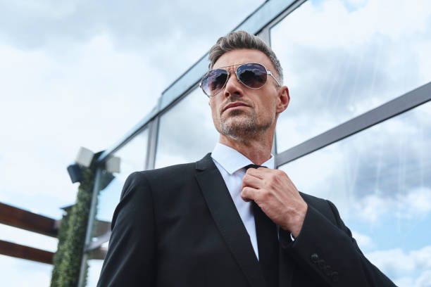istock Confident mature man carrying laptop and adjusting necktie 1332145910